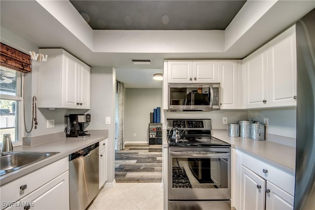 kitchen with white cabinets, stainless steel appliances, light tile patterned flooring, and sink