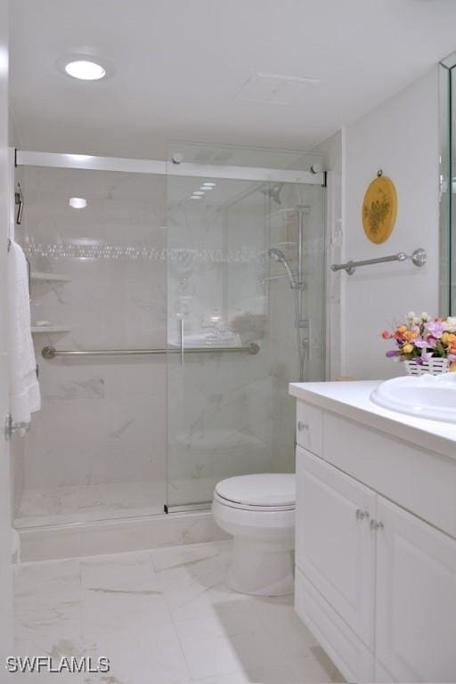 bathroom featuring vanity, a shower with shower door, and toilet