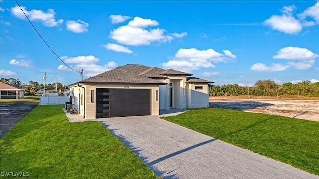 view of front facade with a garage, fence, decorative driveway, a front yard, and stucco siding