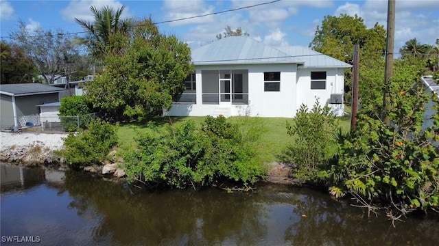 back of property with a water view and a lawn