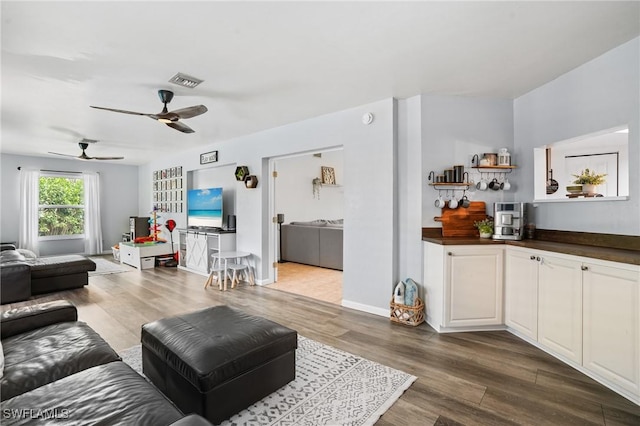 living area with dark wood-type flooring, visible vents, and baseboards