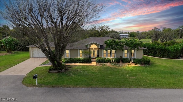 view of front of property featuring driveway, a garage, a front lawn, and stucco siding