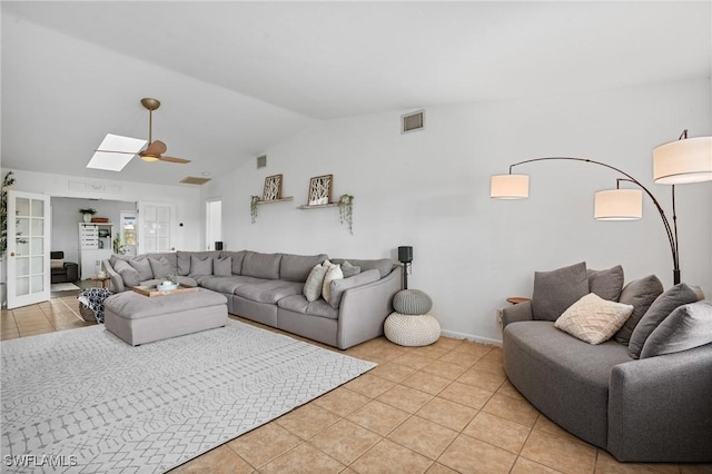 living area featuring lofted ceiling with skylight, visible vents, and light tile patterned floors