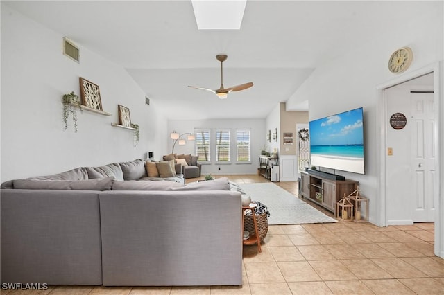 living room with light tile patterned floors, lofted ceiling with skylight, visible vents, and a ceiling fan