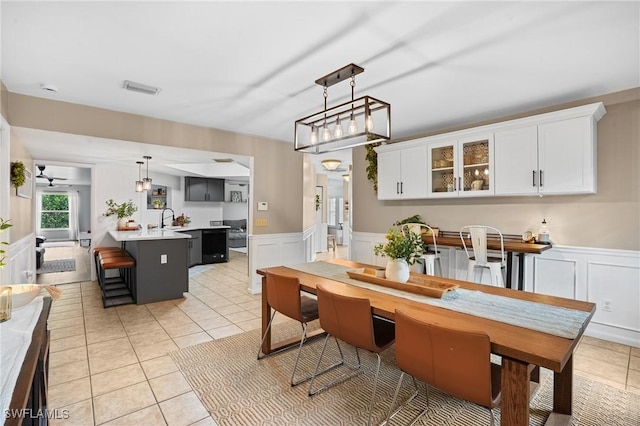 dining space with a wainscoted wall, light tile patterned flooring, and visible vents