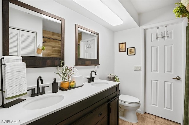 full bathroom featuring double vanity, a sink, toilet, and tile patterned floors