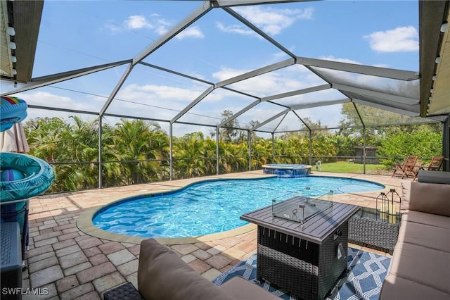 view of swimming pool featuring a patio area, a pool with connected hot tub, and glass enclosure