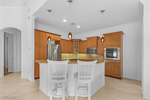 kitchen featuring visible vents, brown cabinetry, arched walkways, decorative backsplash, and appliances with stainless steel finishes