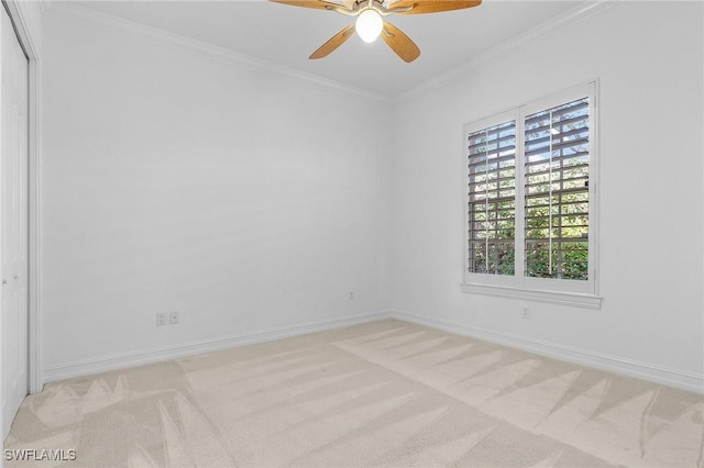 empty room featuring light carpet, crown molding, and baseboards