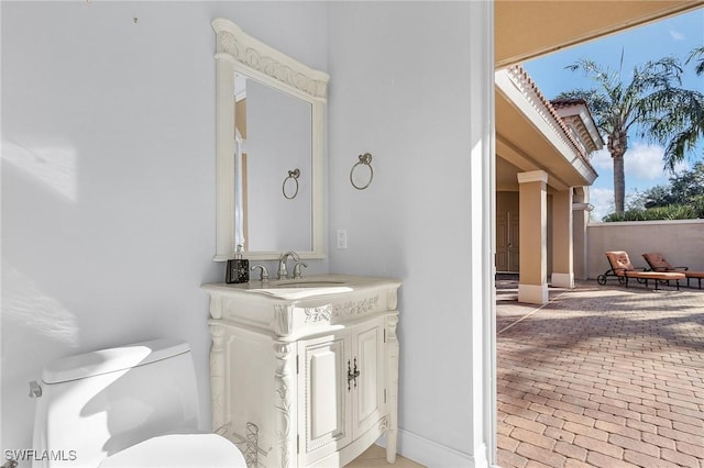 bathroom featuring brick floor, vanity, and toilet