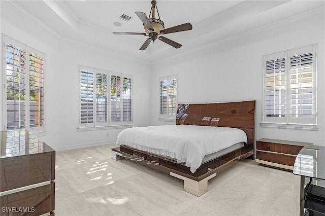 carpeted bedroom with a tray ceiling, visible vents, ornamental molding, ceiling fan, and baseboards