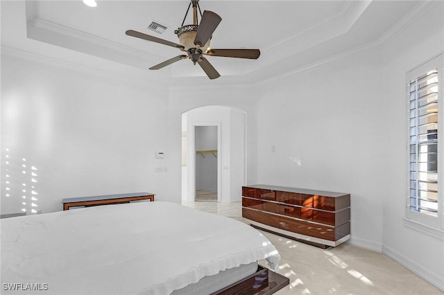 carpeted bedroom with a tray ceiling, arched walkways, visible vents, ornamental molding, and baseboards