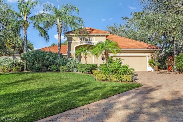 mediterranean / spanish home featuring an attached garage, a front lawn, decorative driveway, and stucco siding