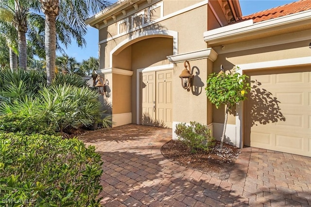 entrance to property featuring a garage and stucco siding