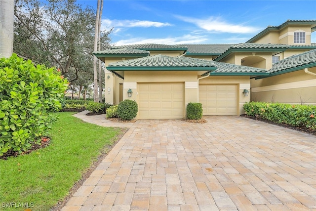 view of front facade with a tiled roof, decorative driveway, a garage, and stucco siding