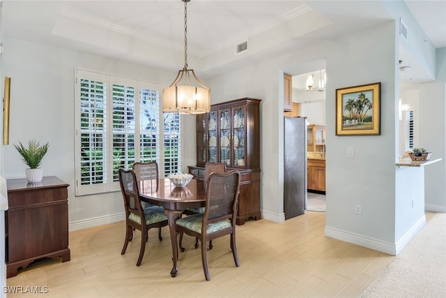 dining room featuring an inviting chandelier, a raised ceiling, visible vents, and light wood-type flooring