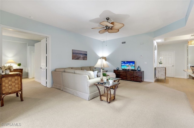 living area featuring visible vents, light colored carpet, baseboards, and a ceiling fan