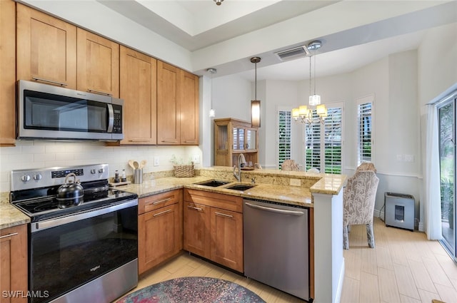 kitchen with tasteful backsplash, appliances with stainless steel finishes, a peninsula, a notable chandelier, and a sink