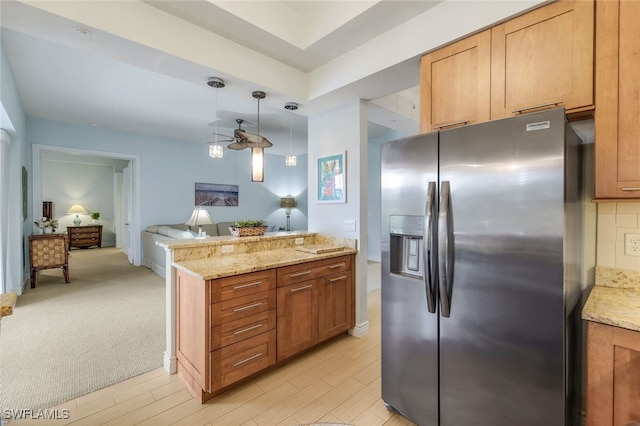 kitchen featuring a ceiling fan, light stone countertops, stainless steel refrigerator with ice dispenser, pendant lighting, and open floor plan