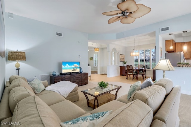 living room featuring visible vents, baseboards, light colored carpet, and a ceiling fan