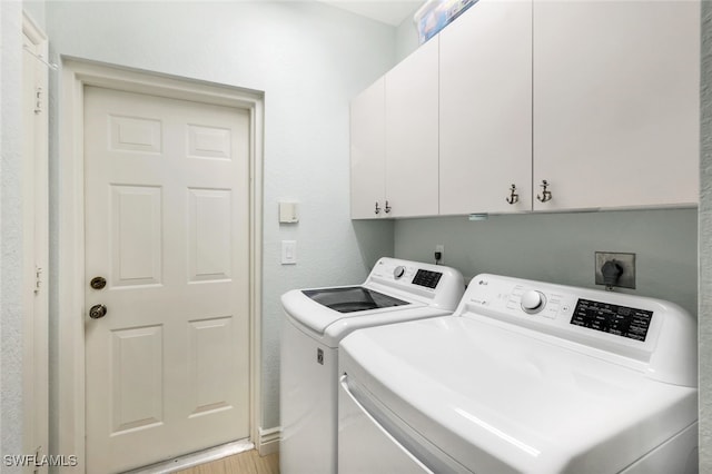 clothes washing area with washer and dryer and cabinet space