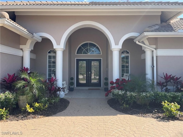 view of exterior entry featuring french doors and stucco siding