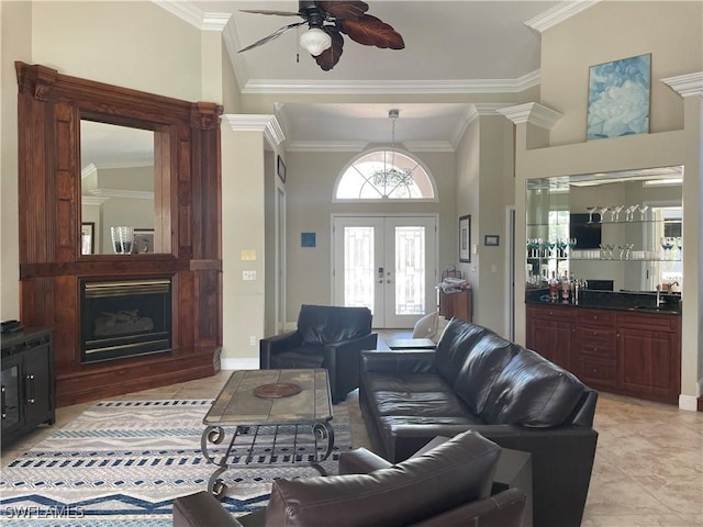 living room with light tile patterned floors, a fireplace with raised hearth, ceiling fan, crown molding, and french doors