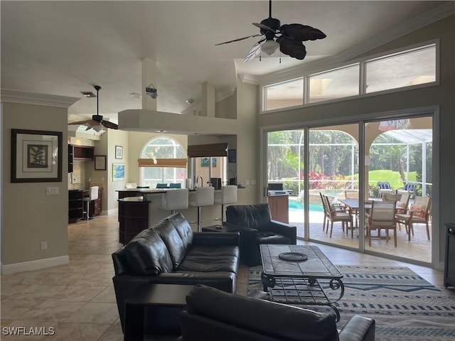 living area featuring light tile patterned floors, ornamental molding, a ceiling fan, and baseboards