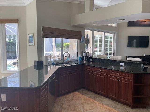 kitchen with dishwasher, a peninsula, dark stone countertops, and a sink