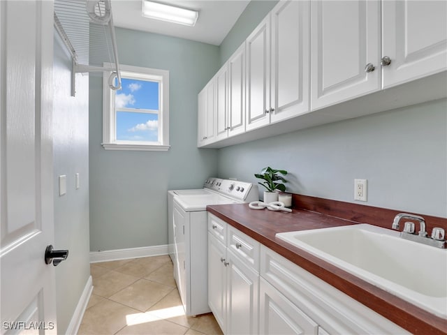 laundry room featuring light tile patterned floors, a sink, baseboards, washer and dryer, and cabinet space