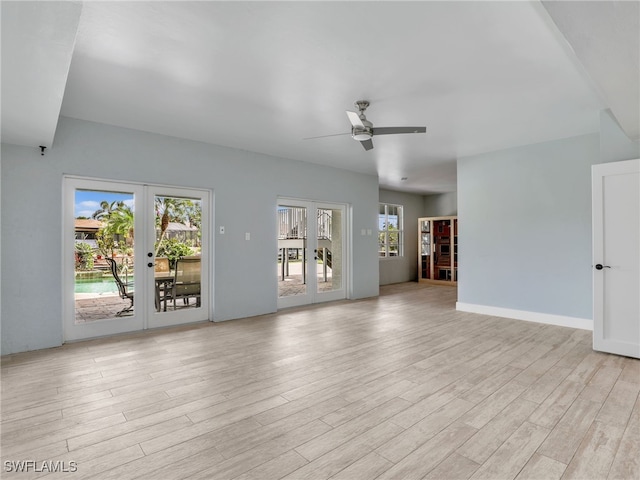 unfurnished living room featuring a ceiling fan, french doors, a healthy amount of sunlight, and light wood-style flooring