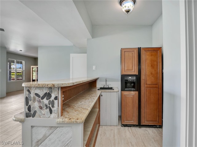 kitchen with light wood-style flooring, a peninsula, a sink, open floor plan, and brown cabinets