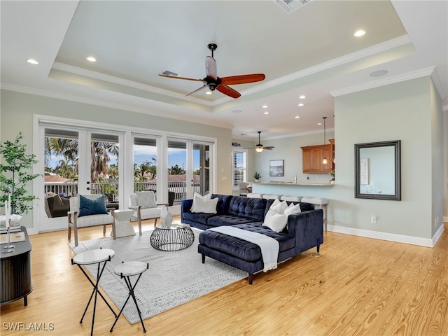 living area featuring french doors, a tray ceiling, plenty of natural light, and light wood-style flooring