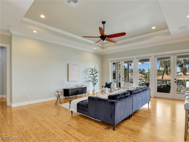 living room with light wood-style flooring, visible vents, a raised ceiling, and french doors