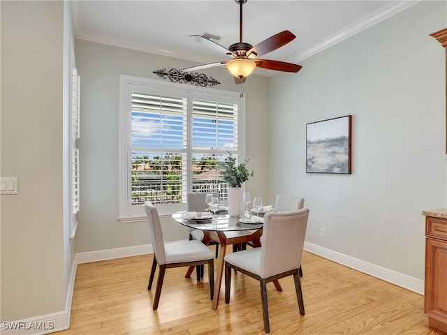 dining room with light wood-style floors, baseboards, and crown molding