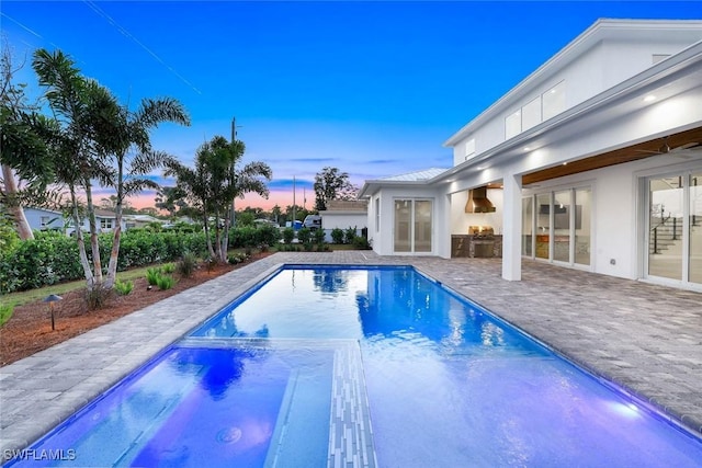 1308 Ridge St, Naples, FL 34103 - pool at dusk featuring a patio area, a pool with connected hot tub, and exterior kitchen