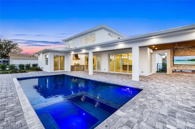 1308 Ridge St, Naples, FL 34103 - back of house at dusk with an outdoor pool, stucco siding, ceiling fan, an in ground hot tub, and a patio area