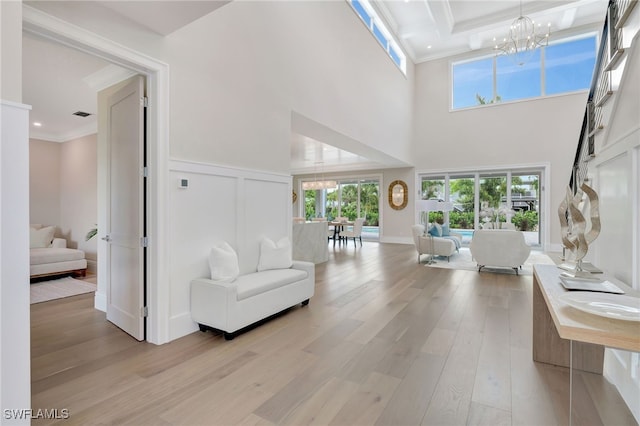 1308 Ridge St, Naples, FL 34103 - living room with a chandelier, light wood-type flooring, crown molding, a decorative wall, and a towering ceiling