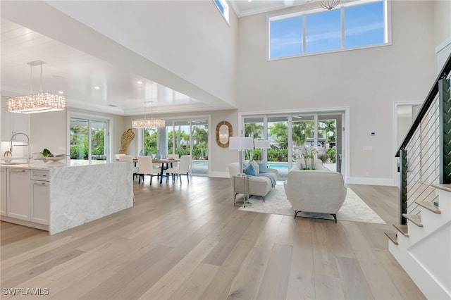 1308 Ridge St, Naples, FL 34103 - living room featuring a chandelier, stairway, light wood-style flooring, ornamental molding, and a towering ceiling