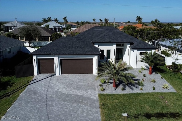 view of front of home featuring decorative driveway, stucco siding, an attached garage, a residential view, and a front lawn