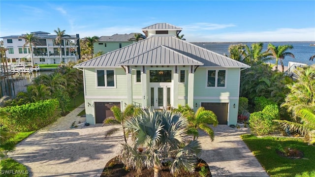 beach home with decorative driveway, a water view, metal roof, and a standing seam roof