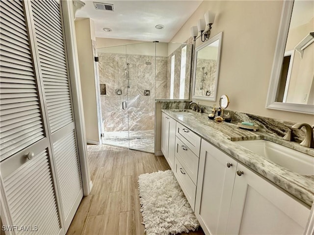 bathroom with a stall shower, wood tiled floor, visible vents, and a sink