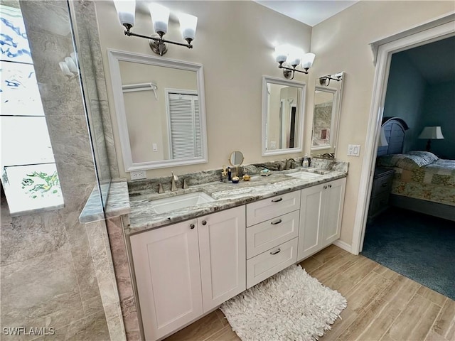 bathroom with double vanity, a sink, a tile shower, and wood finished floors