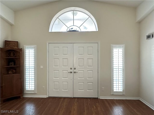 foyer entrance with high vaulted ceiling, dark wood-style flooring, visible vents, and baseboards