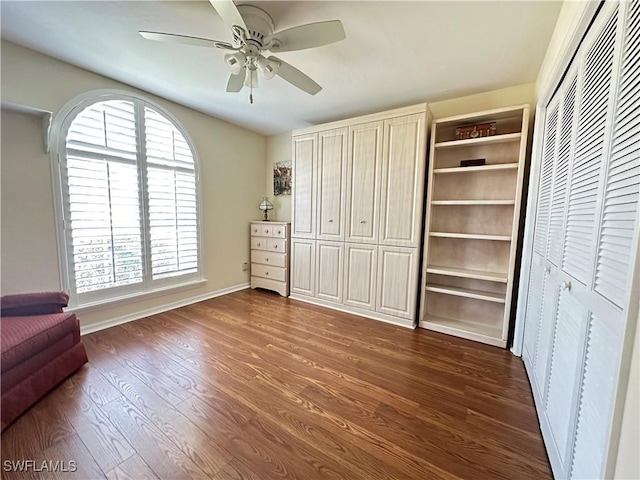 unfurnished bedroom featuring a ceiling fan, dark wood finished floors, and baseboards