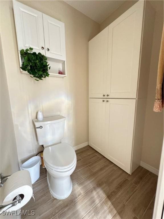 bathroom featuring wood finished floors, toilet, and baseboards