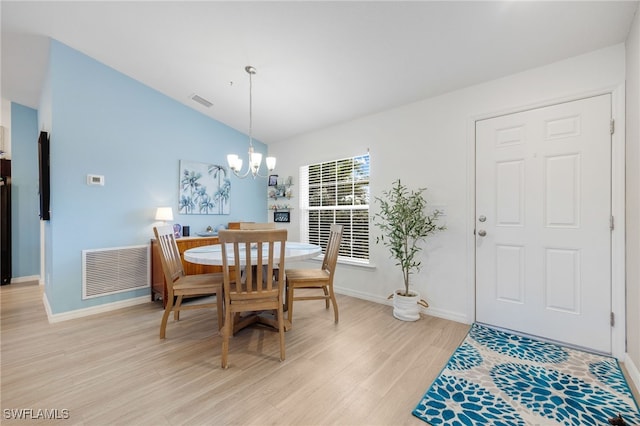 dining space with lofted ceiling, an inviting chandelier, and light hardwood / wood-style flooring