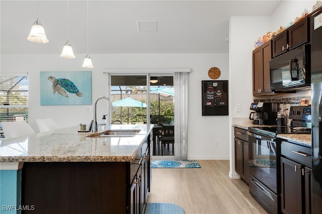 kitchen with sink, dark brown cabinets, black appliances, a center island with sink, and decorative light fixtures