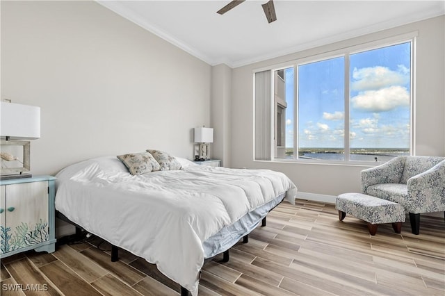 bedroom featuring a water view, wood tiled floor, baseboards, and crown molding