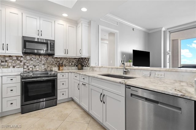 kitchen with white cabinets, appliances with stainless steel finishes, a sink, crown molding, and backsplash